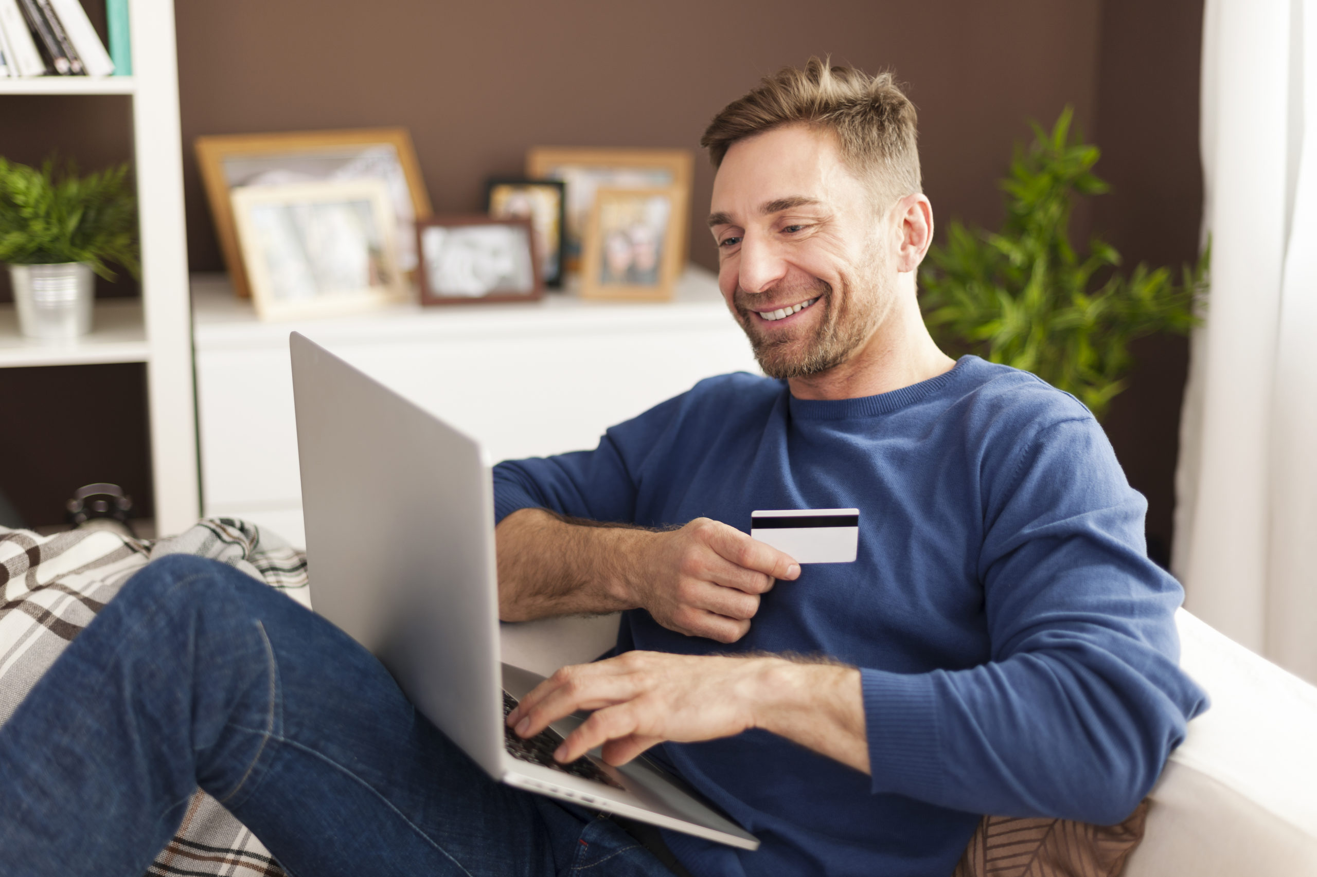homem-sorridente-durante-compras-online-em-casa-scaled.jpg